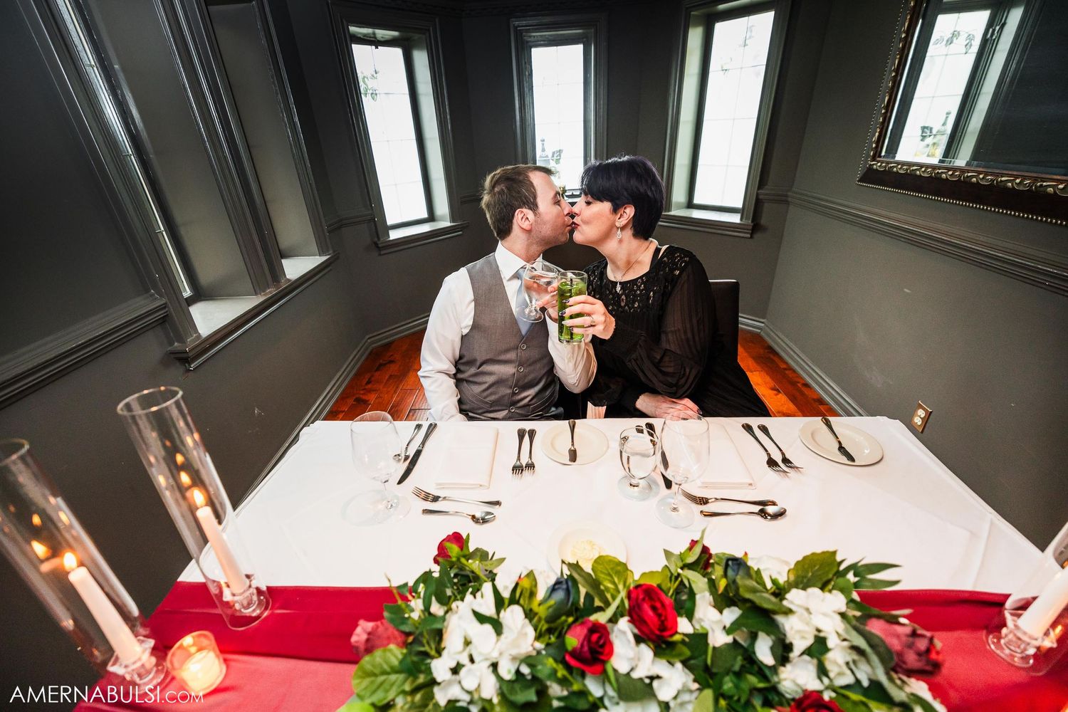 An intimate dining setup with flowers and place settings in a room with large windows.