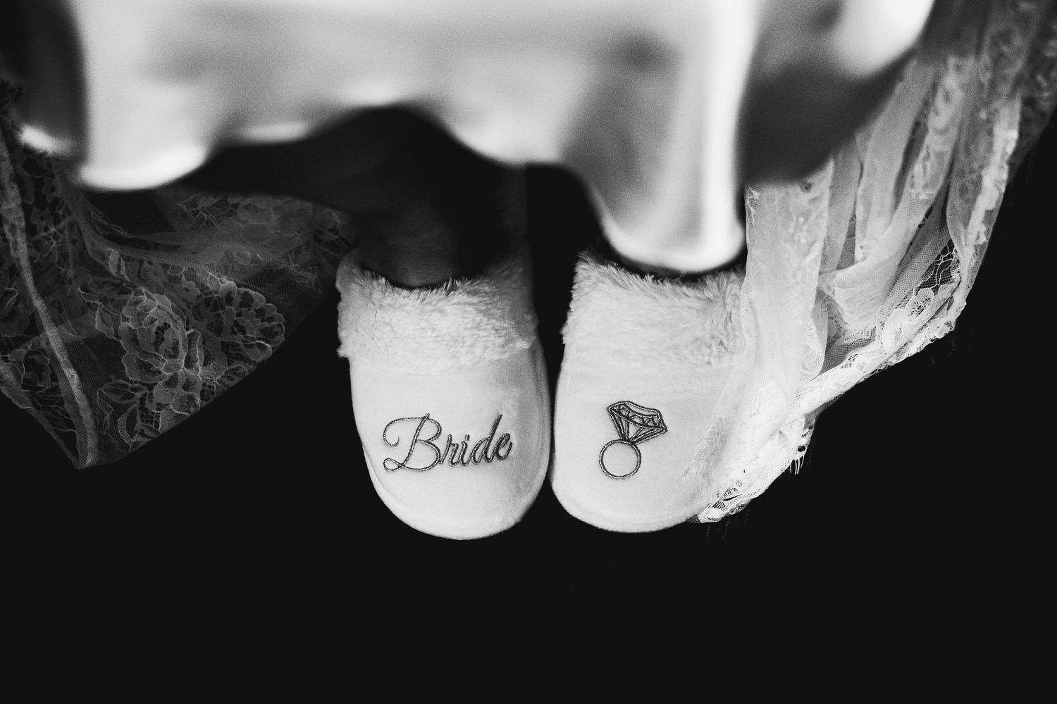 Black and white detail shot of matching bride and wedding ring tattoos on feet.