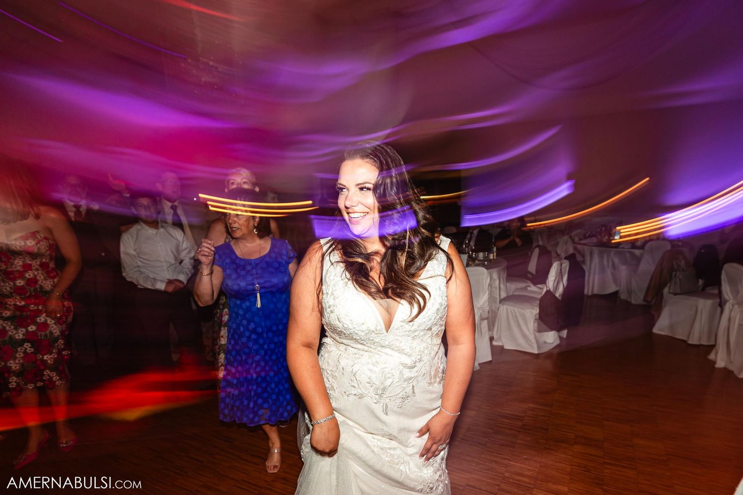 Motion-blurred shot of dancing at a wedding reception with purple ambient lighting.