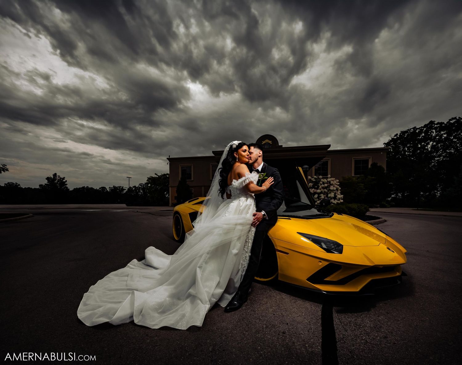 Dramatic wedding photo with dark storm clouds and yellow Lamborghini supercar in the background.