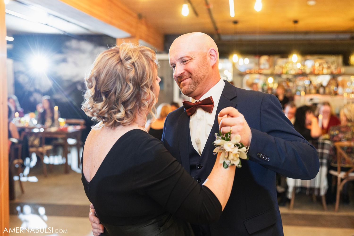 A couple shares a romantic dance at a formal event in an indoor venue.