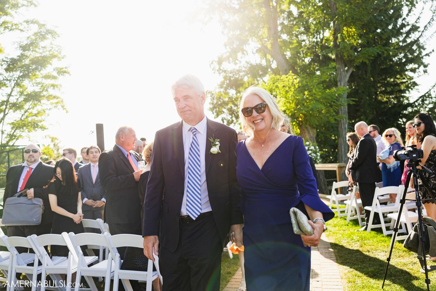 Guests arriving at an outdoor wedding ceremony on a sunny summer day.