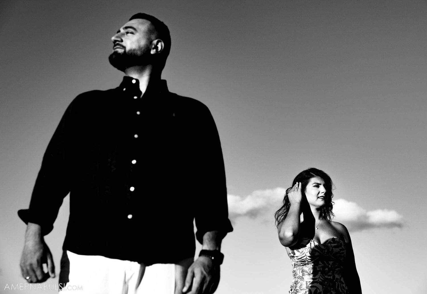 Artistic black and white portrait of couple against dramatic sky.