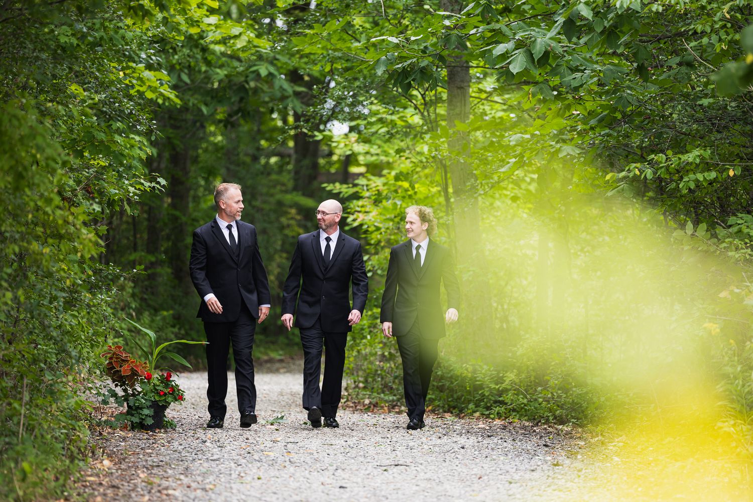 Dignitaries walking on a forest path surrounded by lush green trees and foliage in spring.