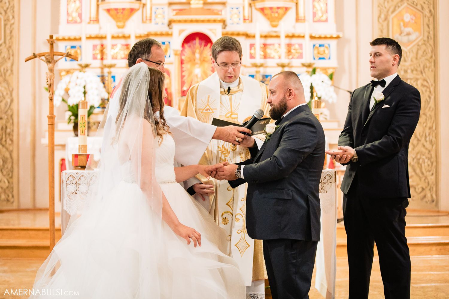 Panoramic view of a wedding ceremony in an ornately decorated church with golden details.