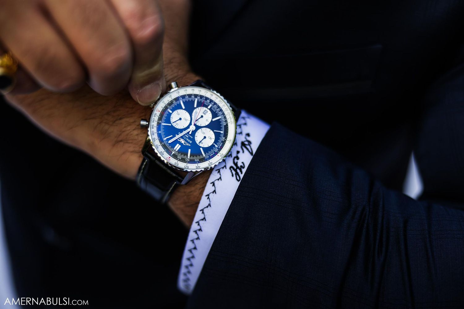 Close-up of an elegant blue chronograph watch on formal attire.