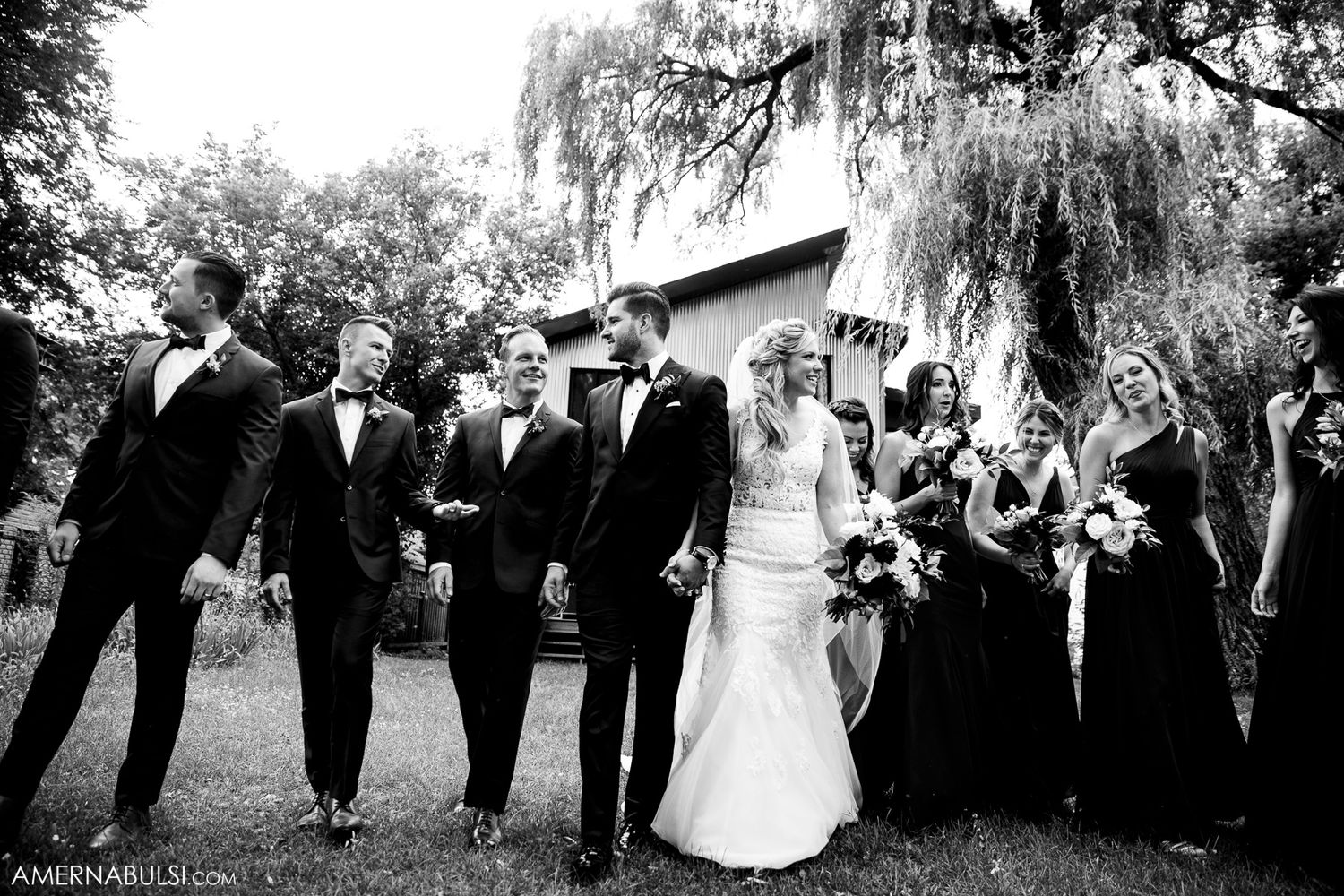 Wedding party poses under weeping willow trees in black and white photography.