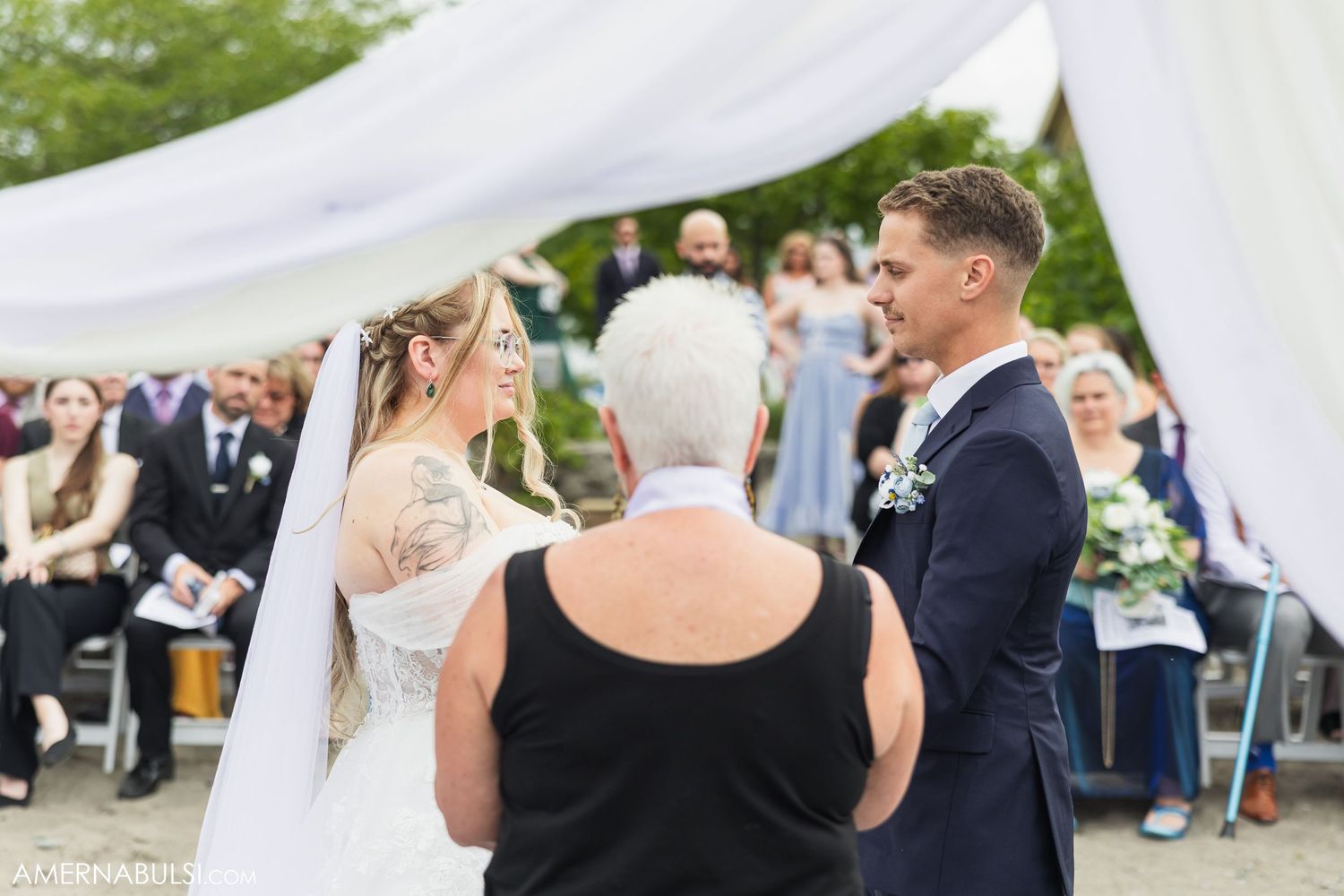 Wedding guests watch a ceremony on a sunny outdoor beach.