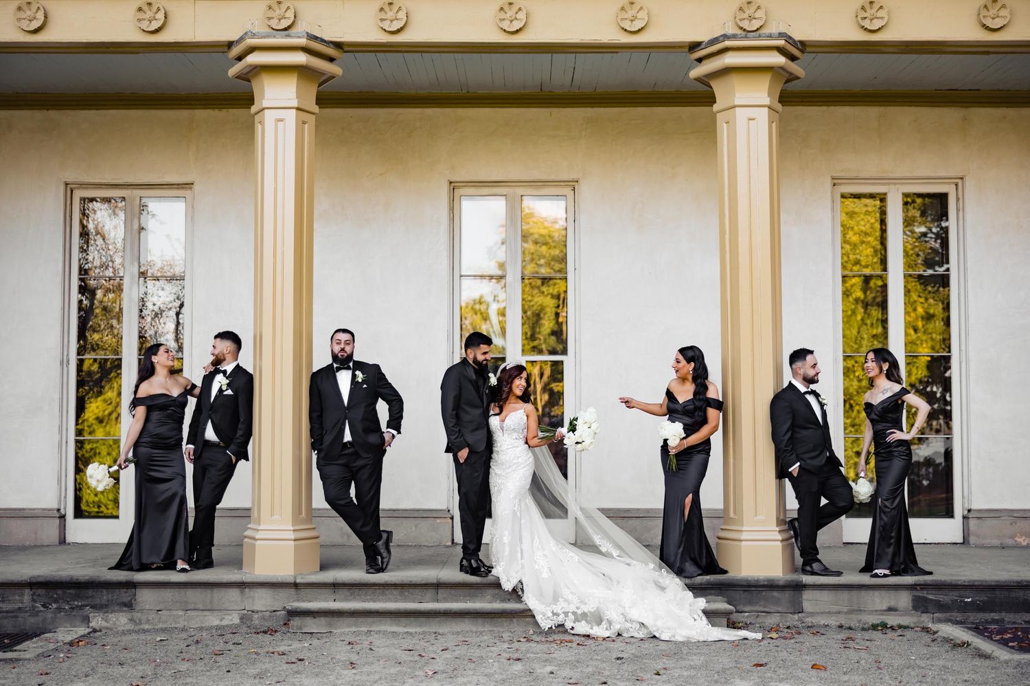 Wedding party arranged stylishly against classical architecture.