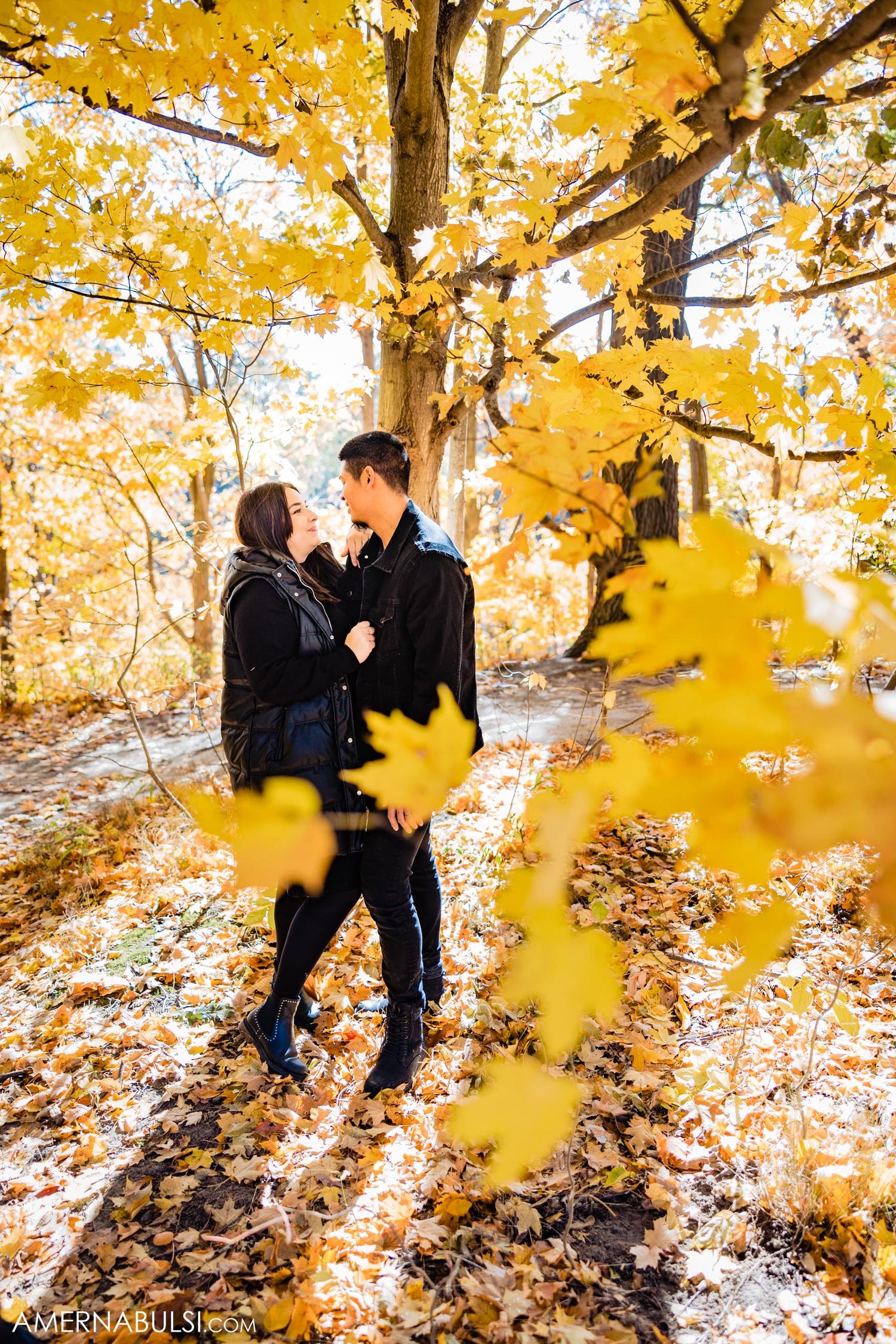 A romantic autumn scene with couple among bright yellow fall foliage.