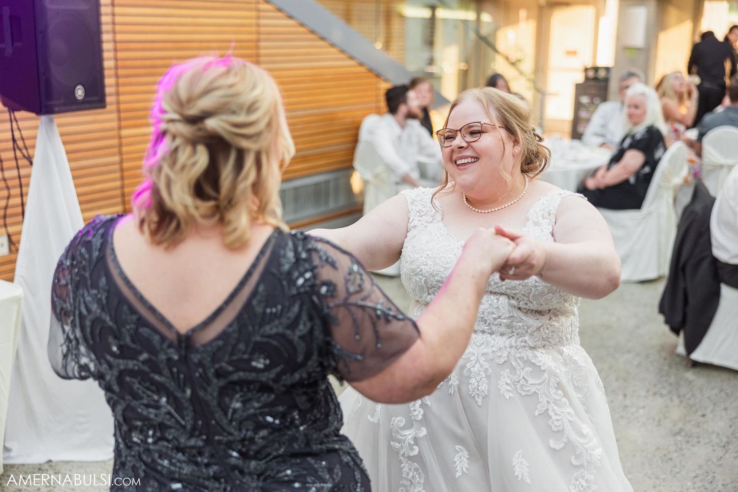 Wedding guests dance and celebrate together at an indoor reception venue.