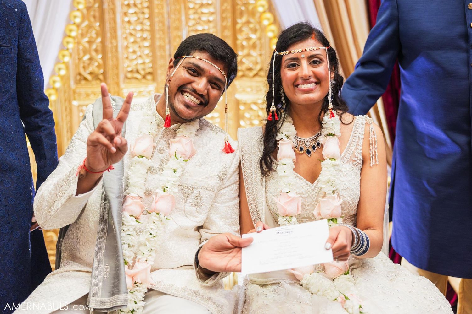 A couple in traditional Indian wedding attire share a joyful moment during their ceremony.