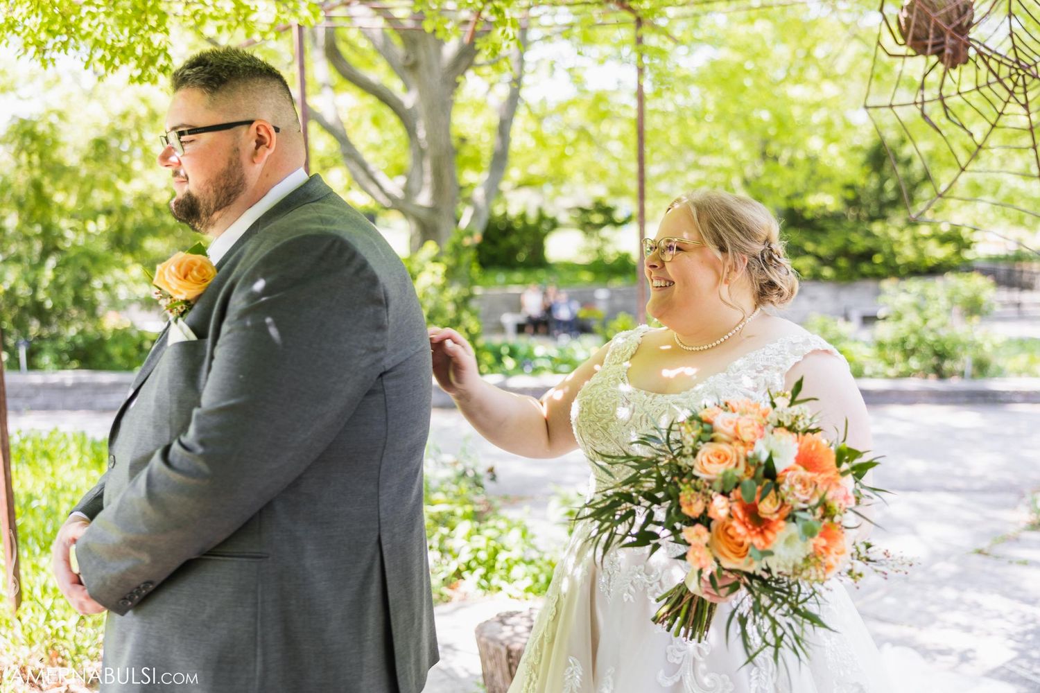 Candid moment between newlyweds during outdoor garden ceremony with peach florals.