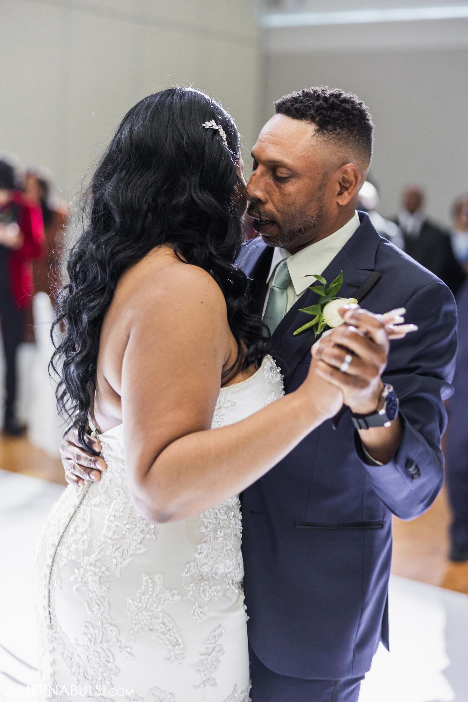 Newlyweds share an intimate kiss in front of their wedding cake.