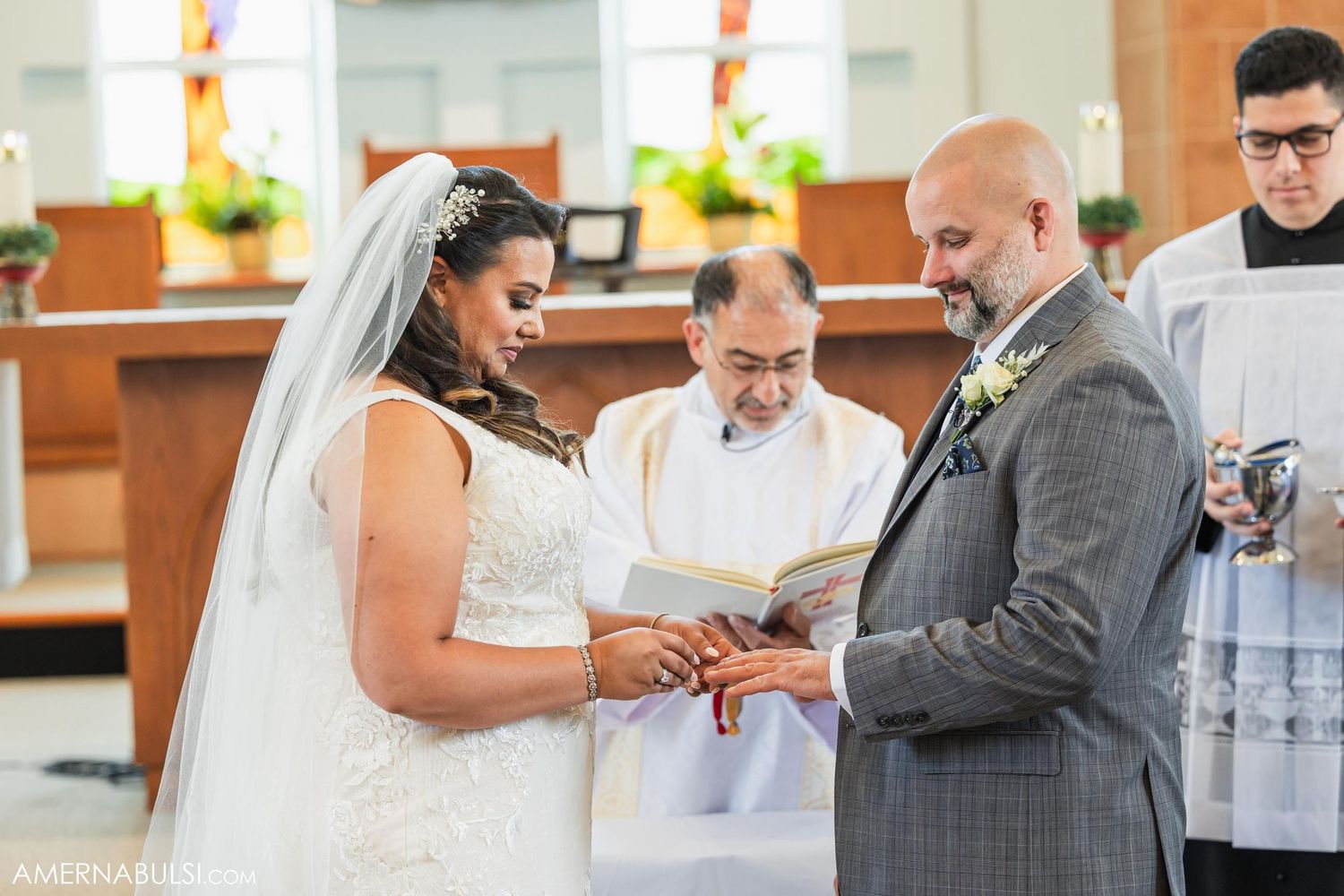 A couple exchanges rings during their wedding ceremony as an officiant presides.