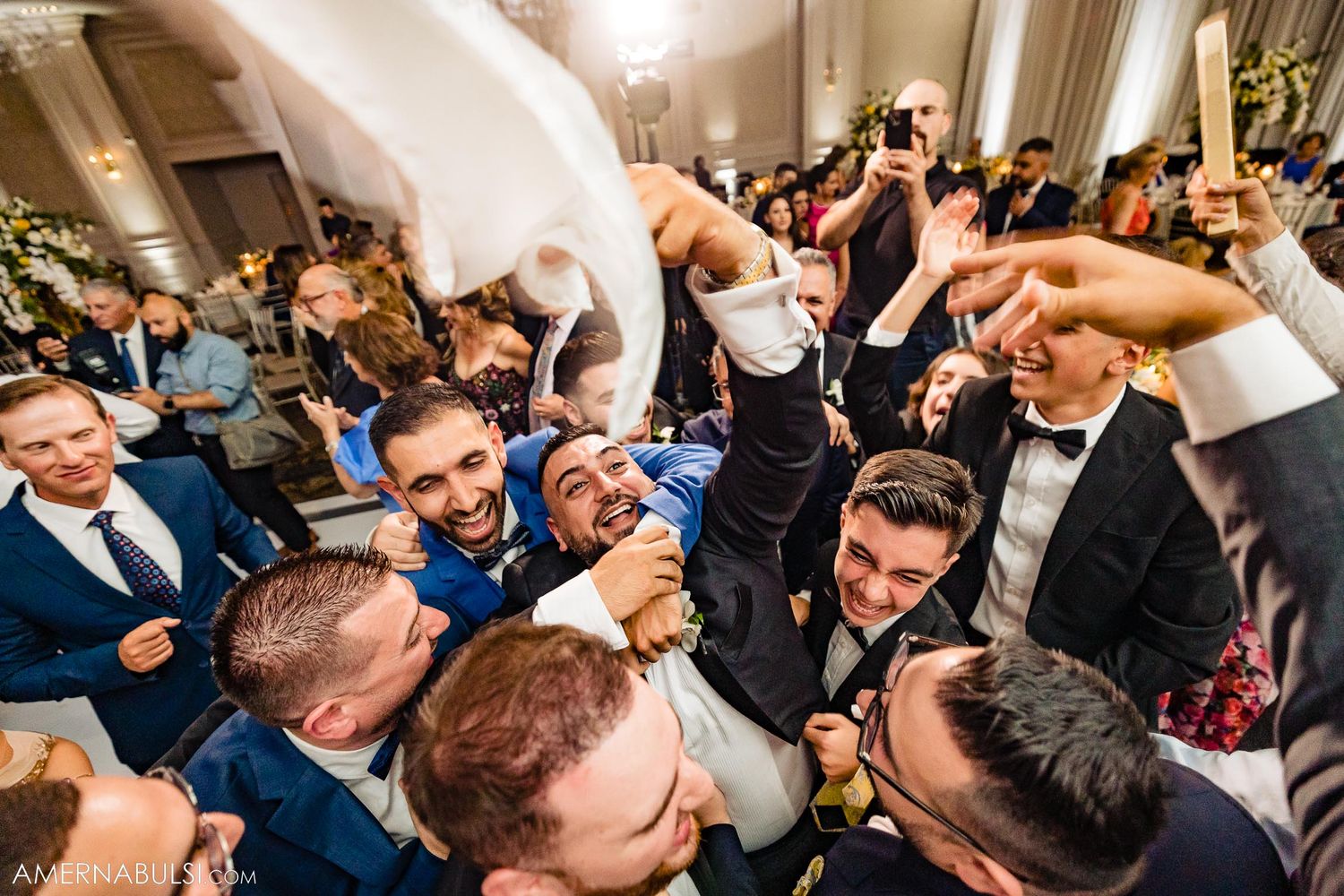 Enthusiastic wedding guests create an energetic crowd moment during a reception celebration.