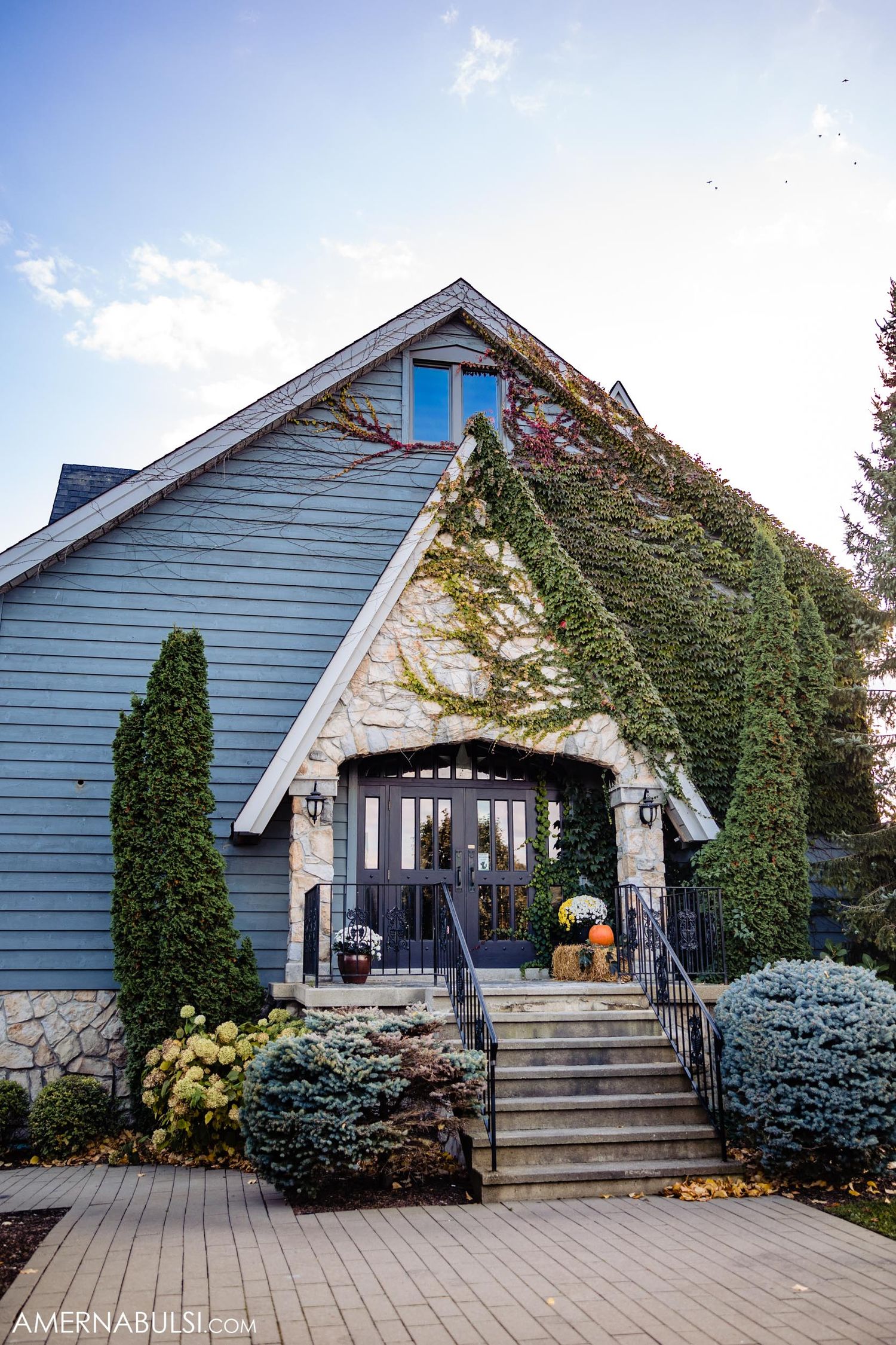 Elegant building exterior with ivy-covered walls, stone accents and seasonal pumpkin decorations.