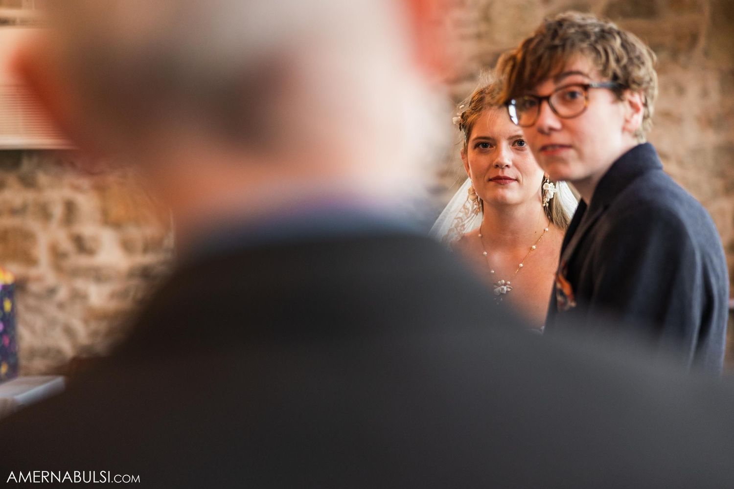 An intimate wedding moment captured against a rustic stone wall background.