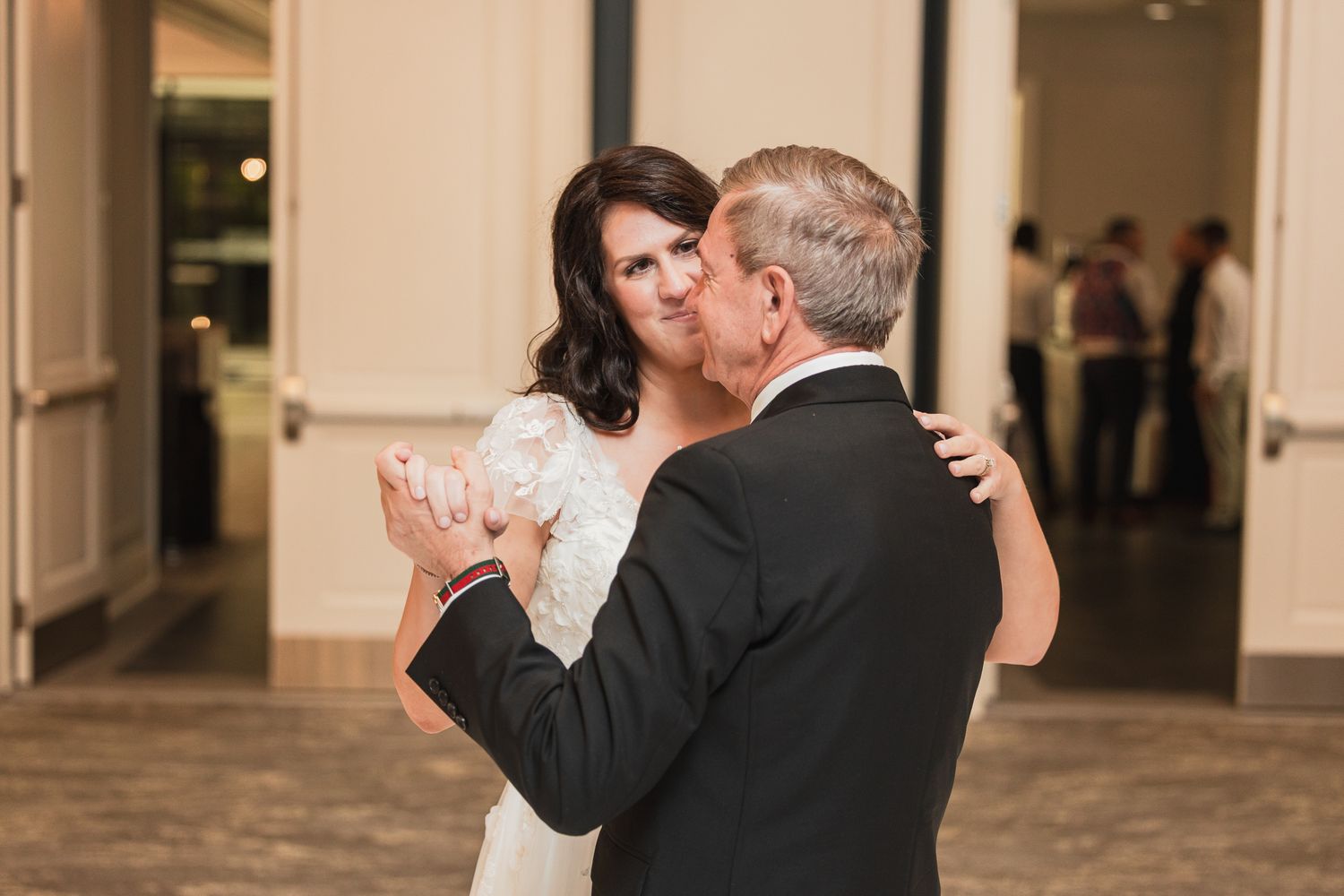 Bride and father sharing an emotional first dance at wedding reception in elegant venue.
