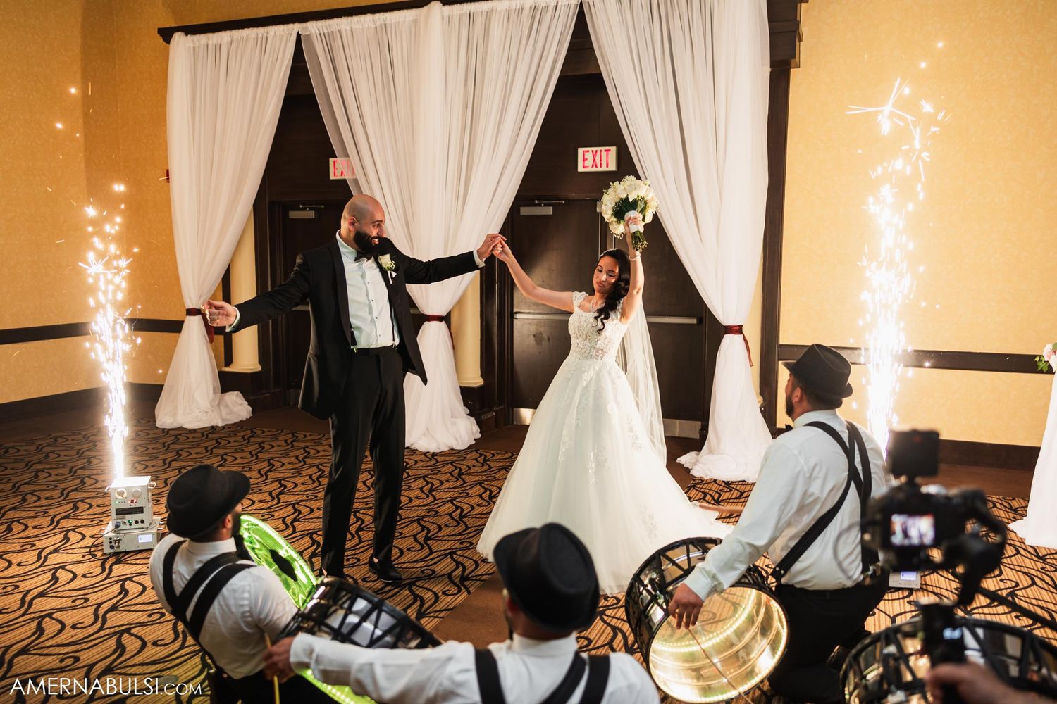 Couple dancing at their wedding reception with sparklers and musicians in the background.