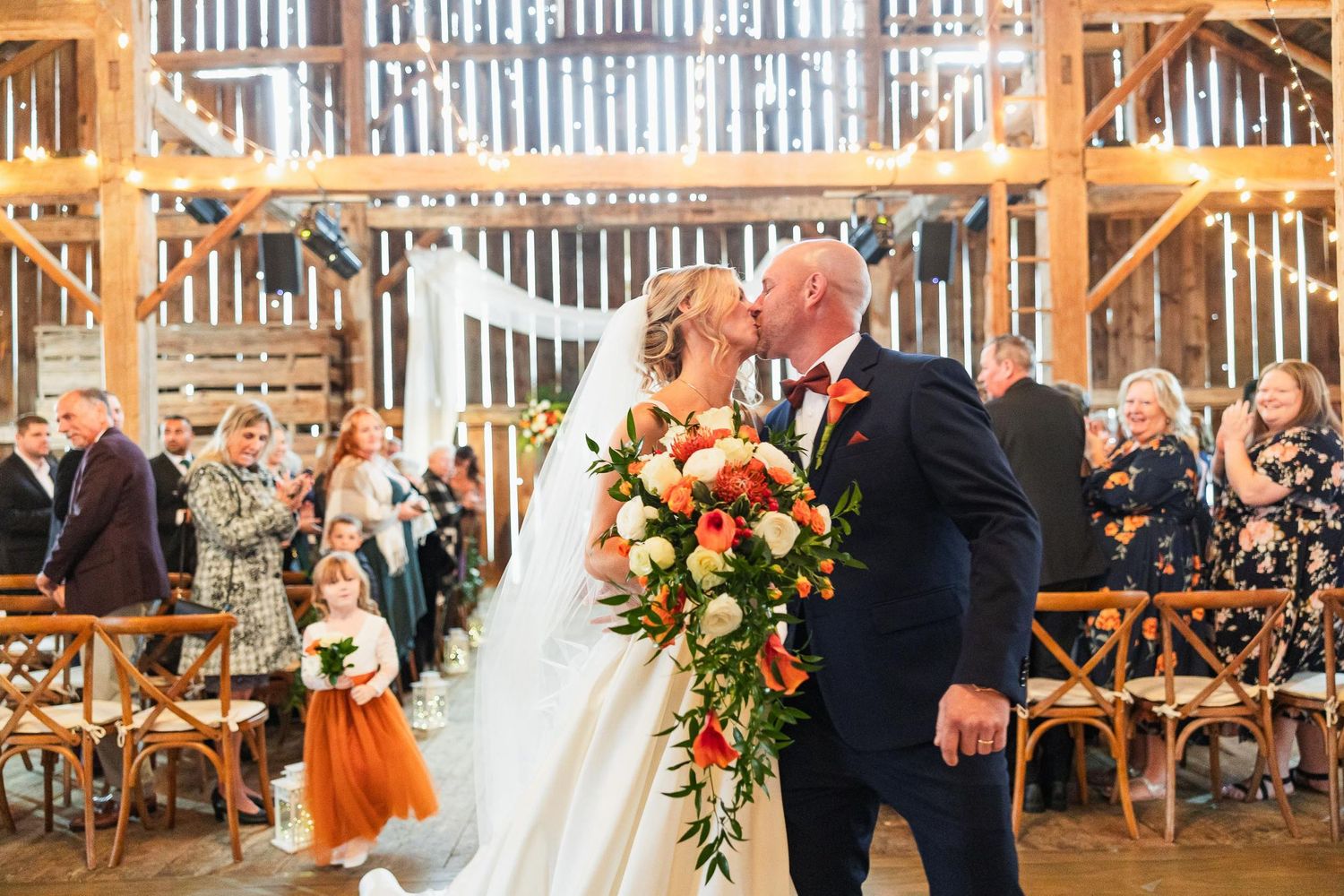 A celebration moment in a rustic barn wedding venue with wooden beams and warm lighting.