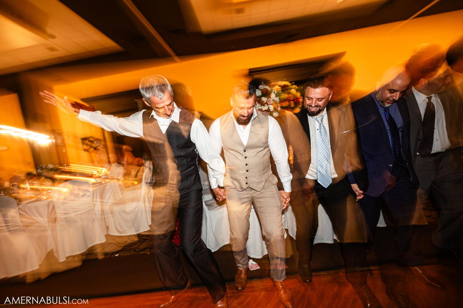 Wedding guests dance and celebrate on the dance floor with motion blur effects.