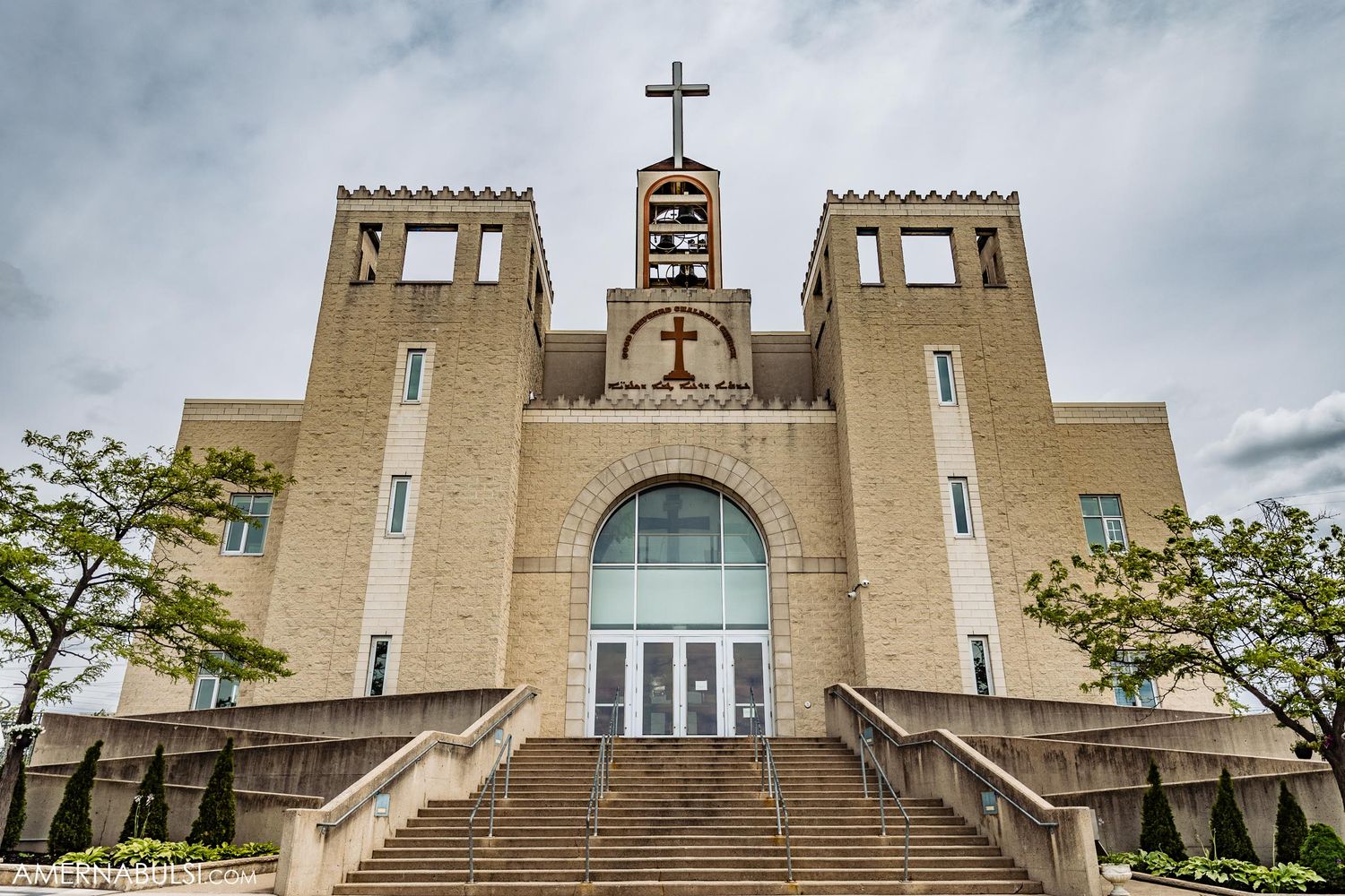 Exterior view of modern church building with twin towers and large cross on top.