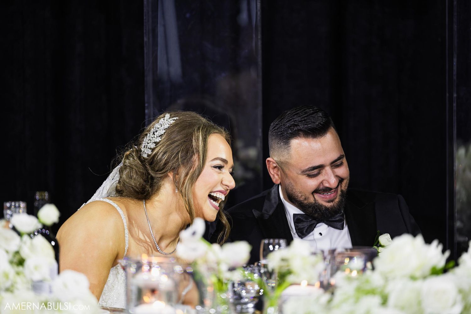 A joyful candid moment shared between a couple at their wedding reception table.