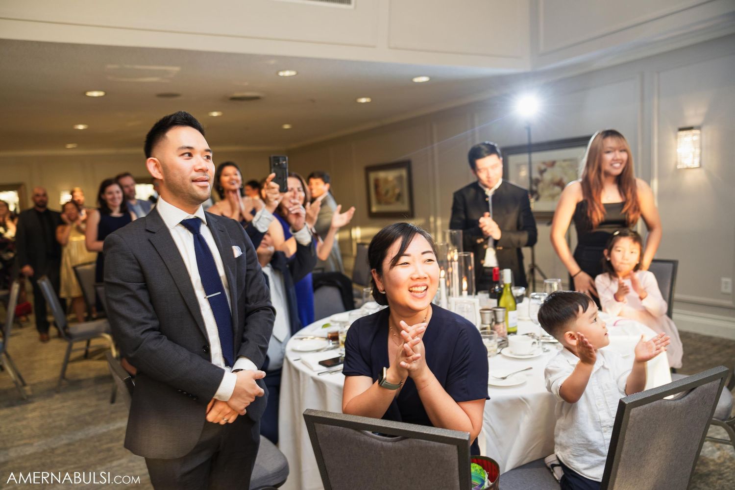 Wedding guests react with joy and excitement during a reception celebration.
