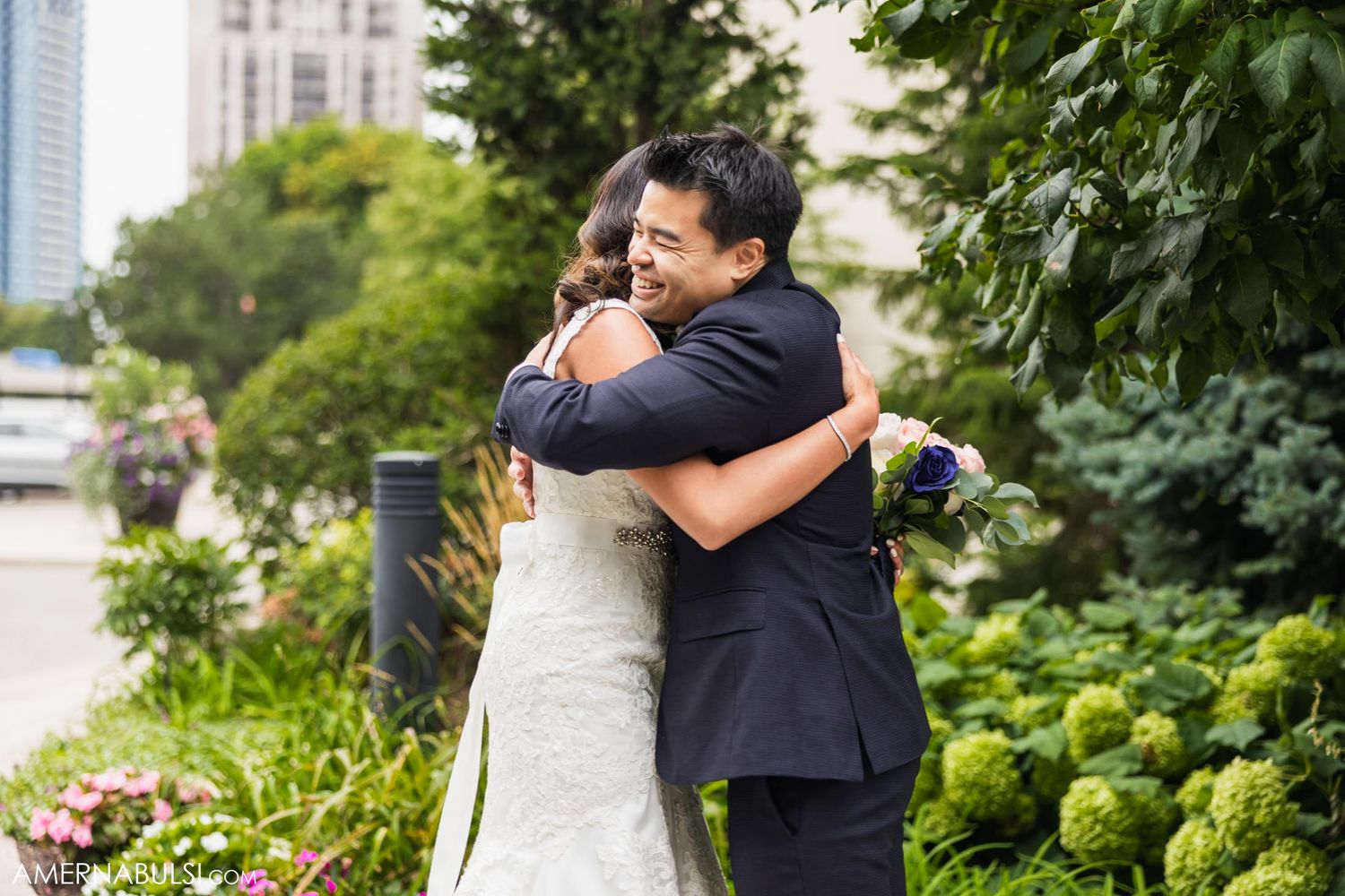 Emotional embrace during outdoor wedding ceremony in urban garden setting.