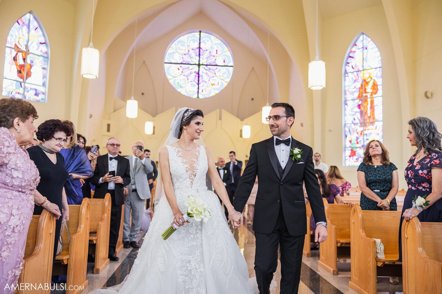 A traditional church wedding ceremony takes place under arched ceilings and stained glass windows.