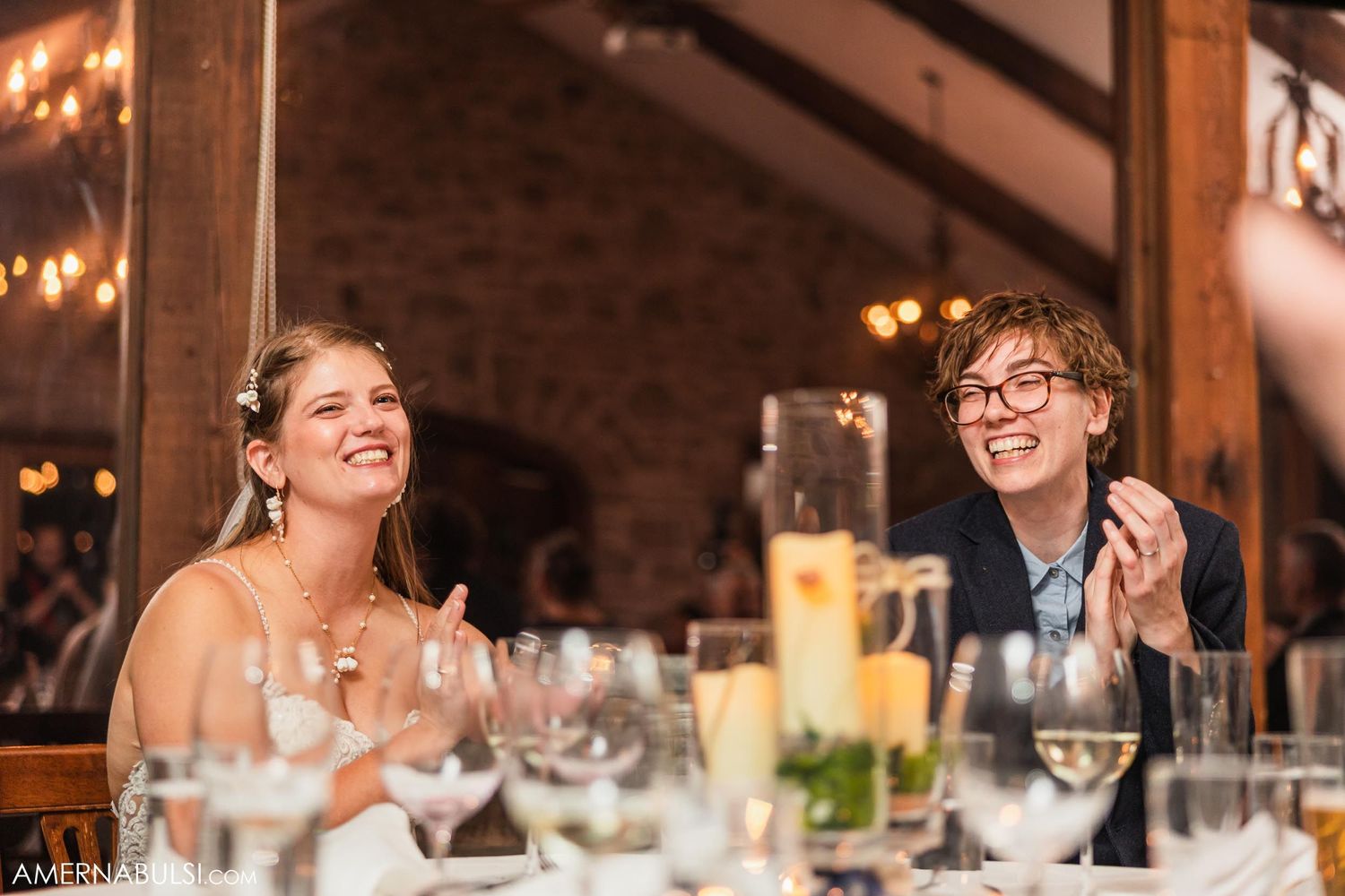 Wedding reception dinner with table settings and drinks in a rustic stone venue.