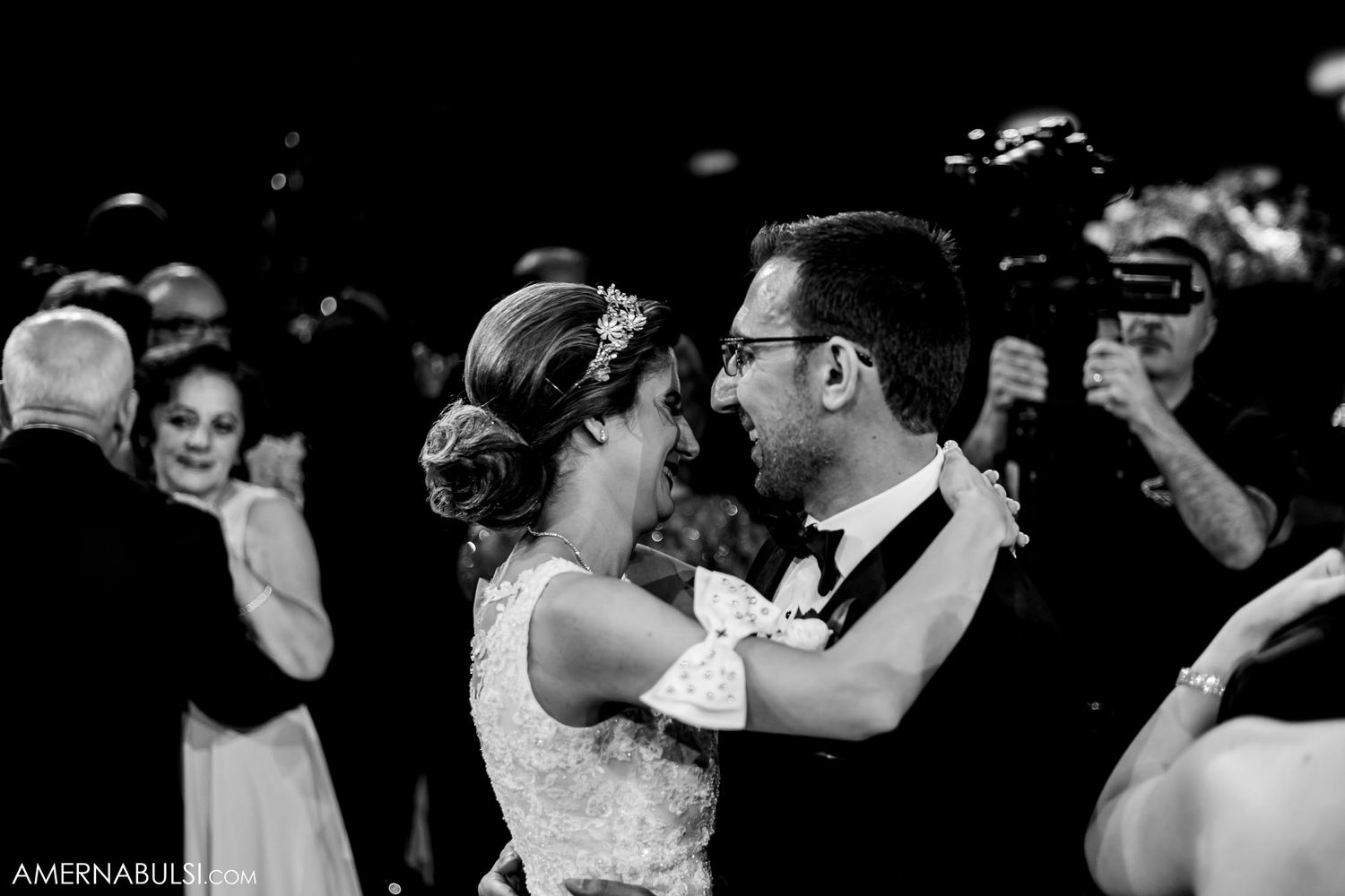 Black and white photo of a romantic wedding dance moment surrounded by guests.