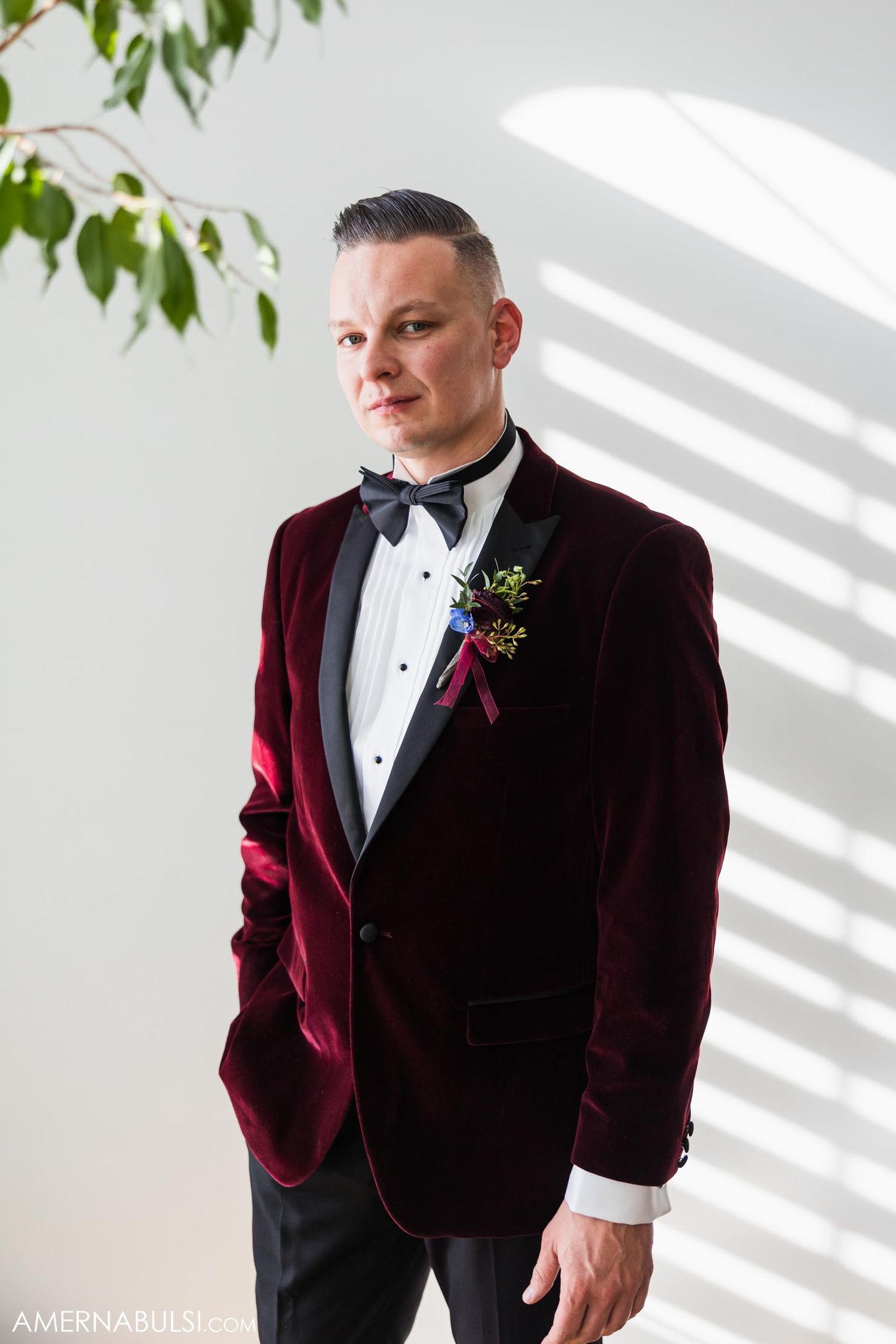 Formal portrait showing burgundy velvet tuxedo jacket with black bow tie and boutonniere.