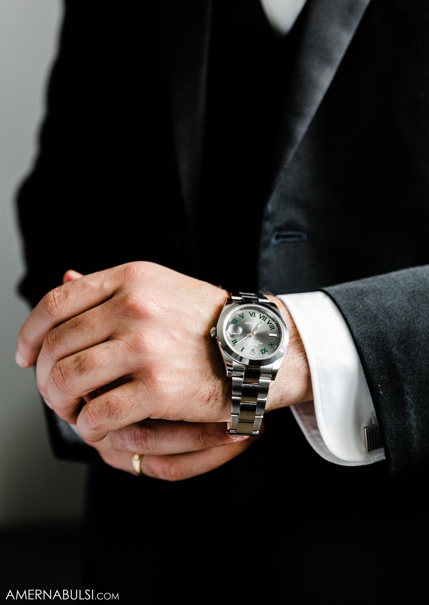 Elegant wristwatch on formal suit sleeve with metallic band and chronograph face.