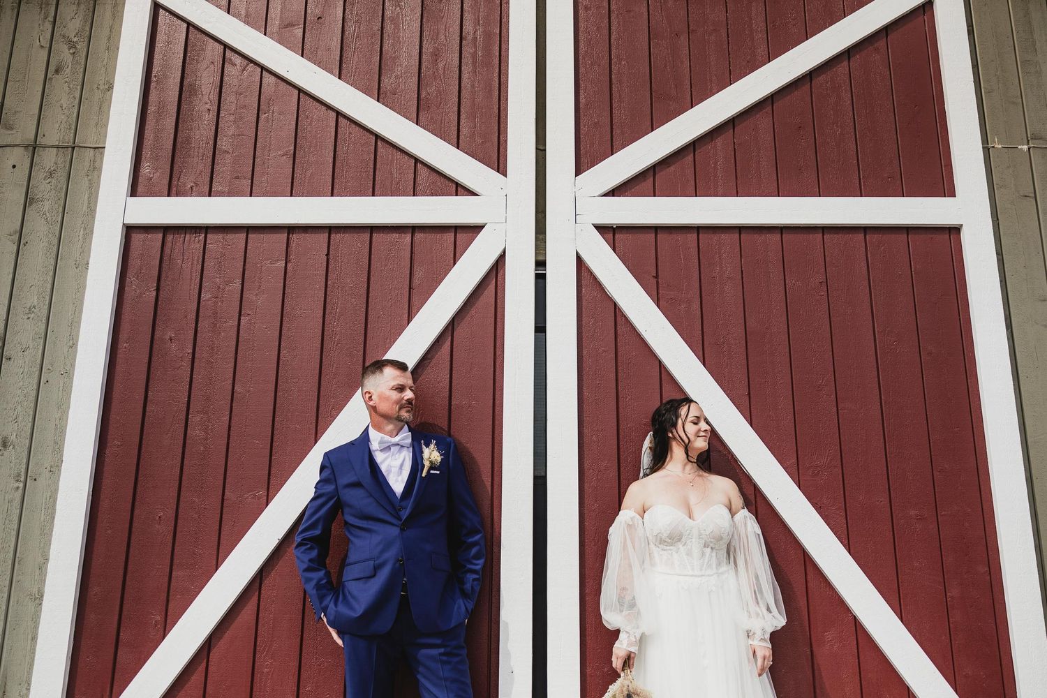 Wedding portrait against geometric white patterns on red barn door.
