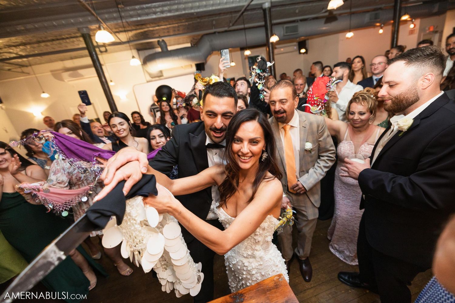 Wedding reception dance party with guests celebrating in an indoor venue.