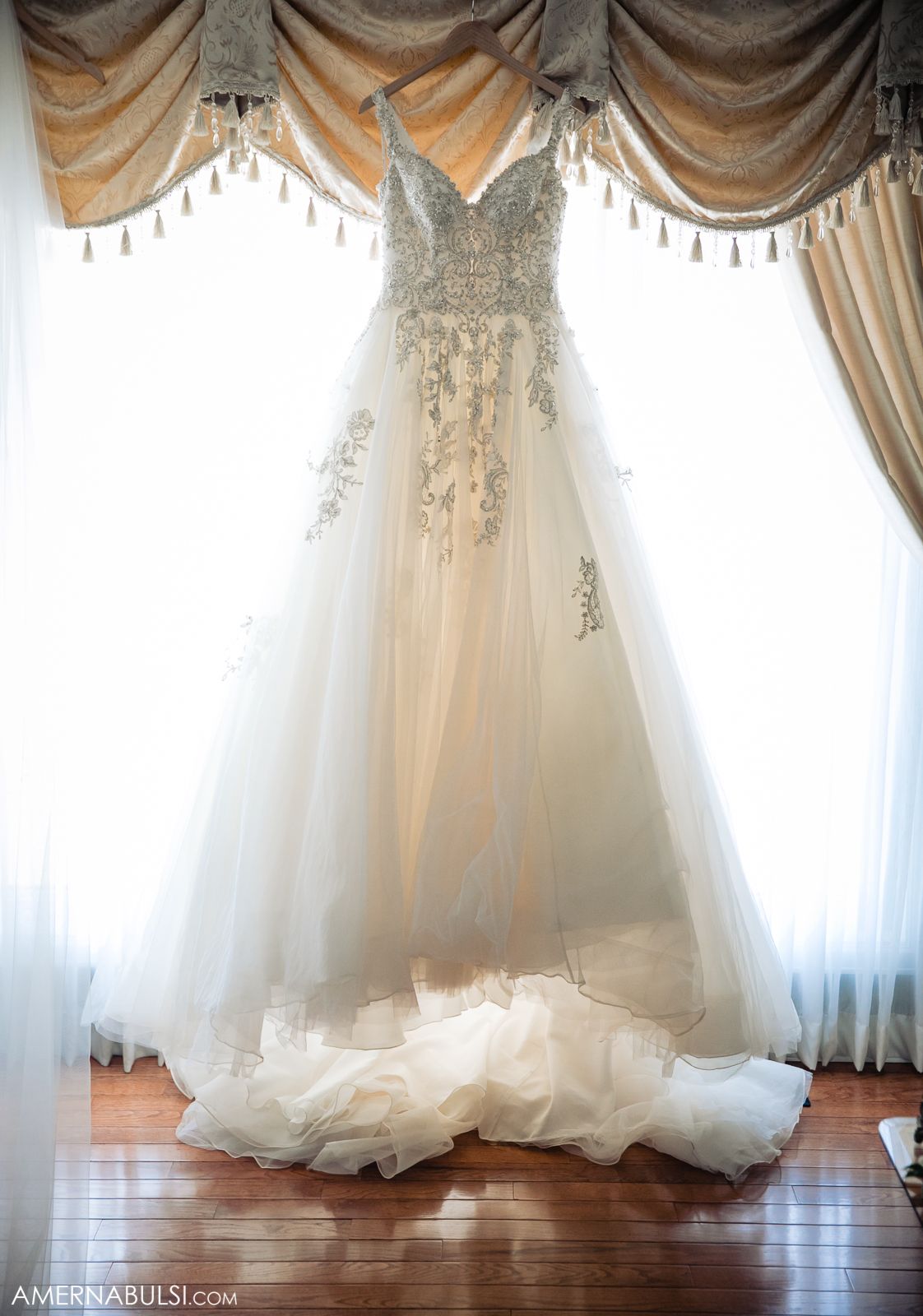 Wedding dress details showing delicate lace and tulle fabric against elegant drapes.