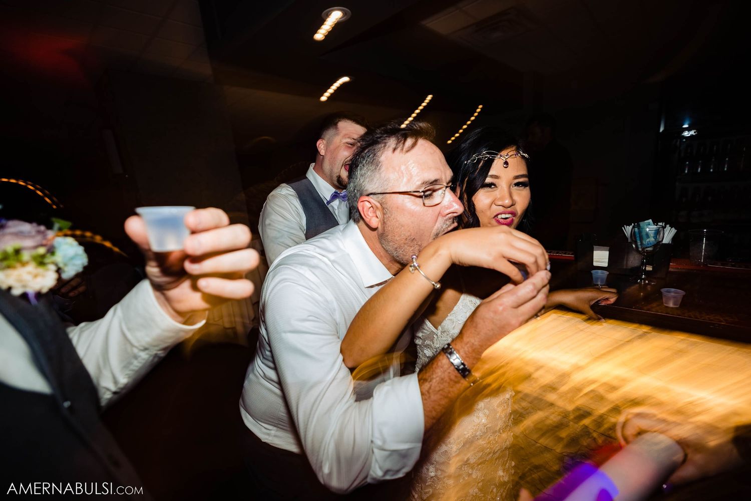 People enjoying drinks at a wooden bar during a celebration.