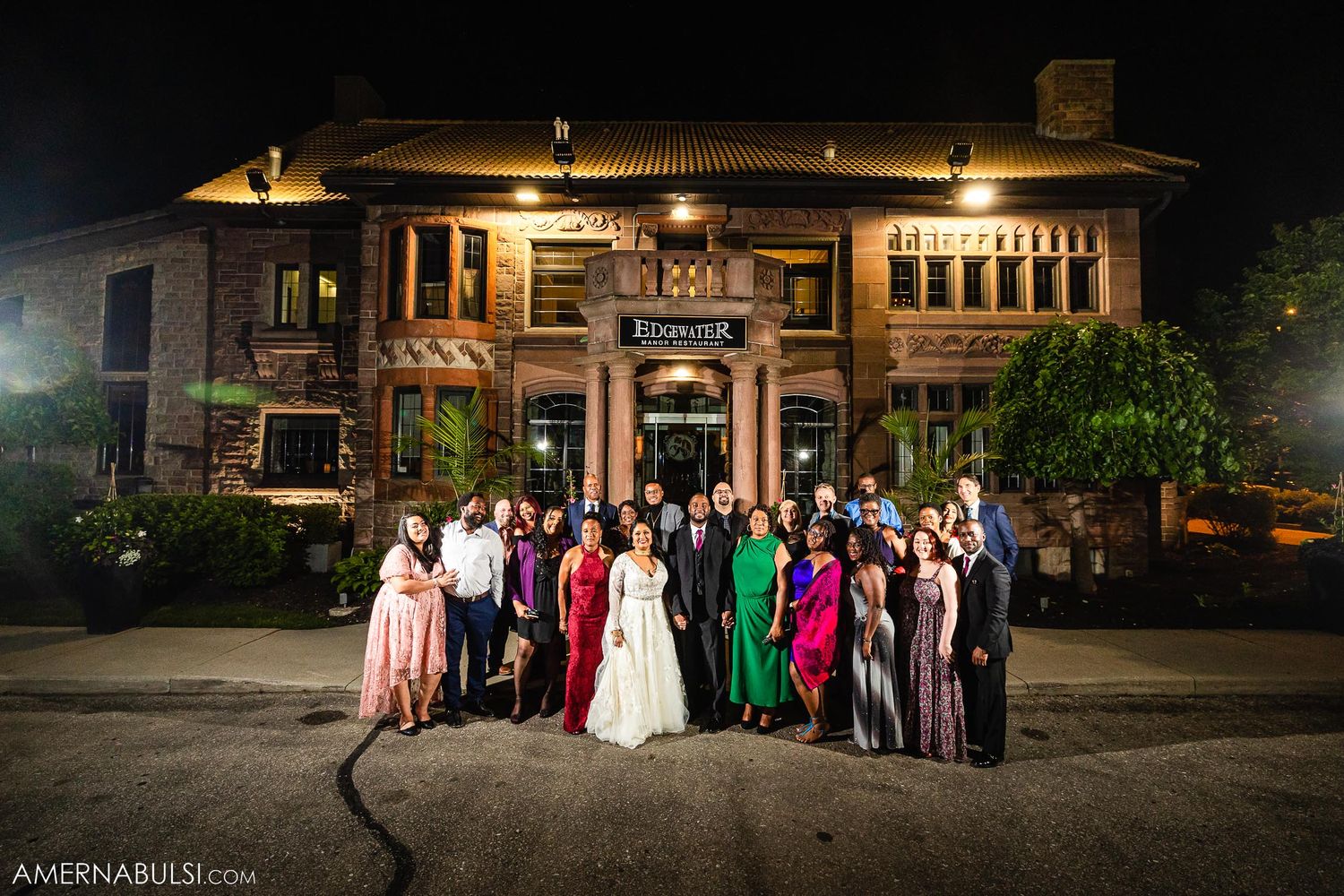 Large group gathered for an evening event photo in front of an illuminated historic building.
