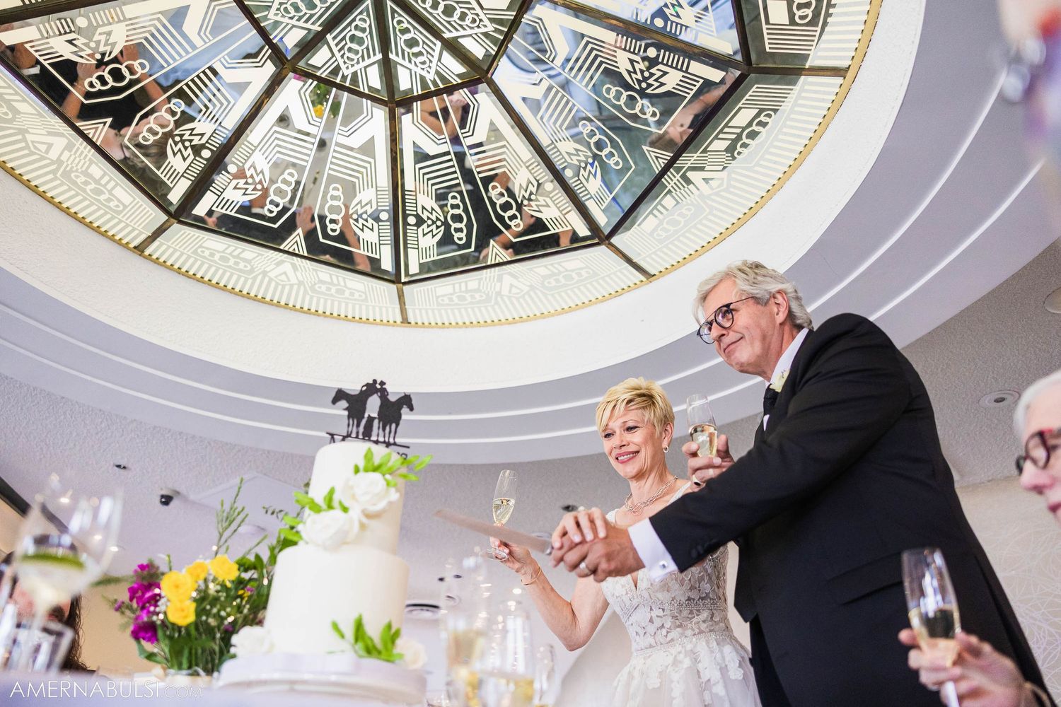 Wedding celebration under ornate domed ceiling with decorative details and floral arrangements.