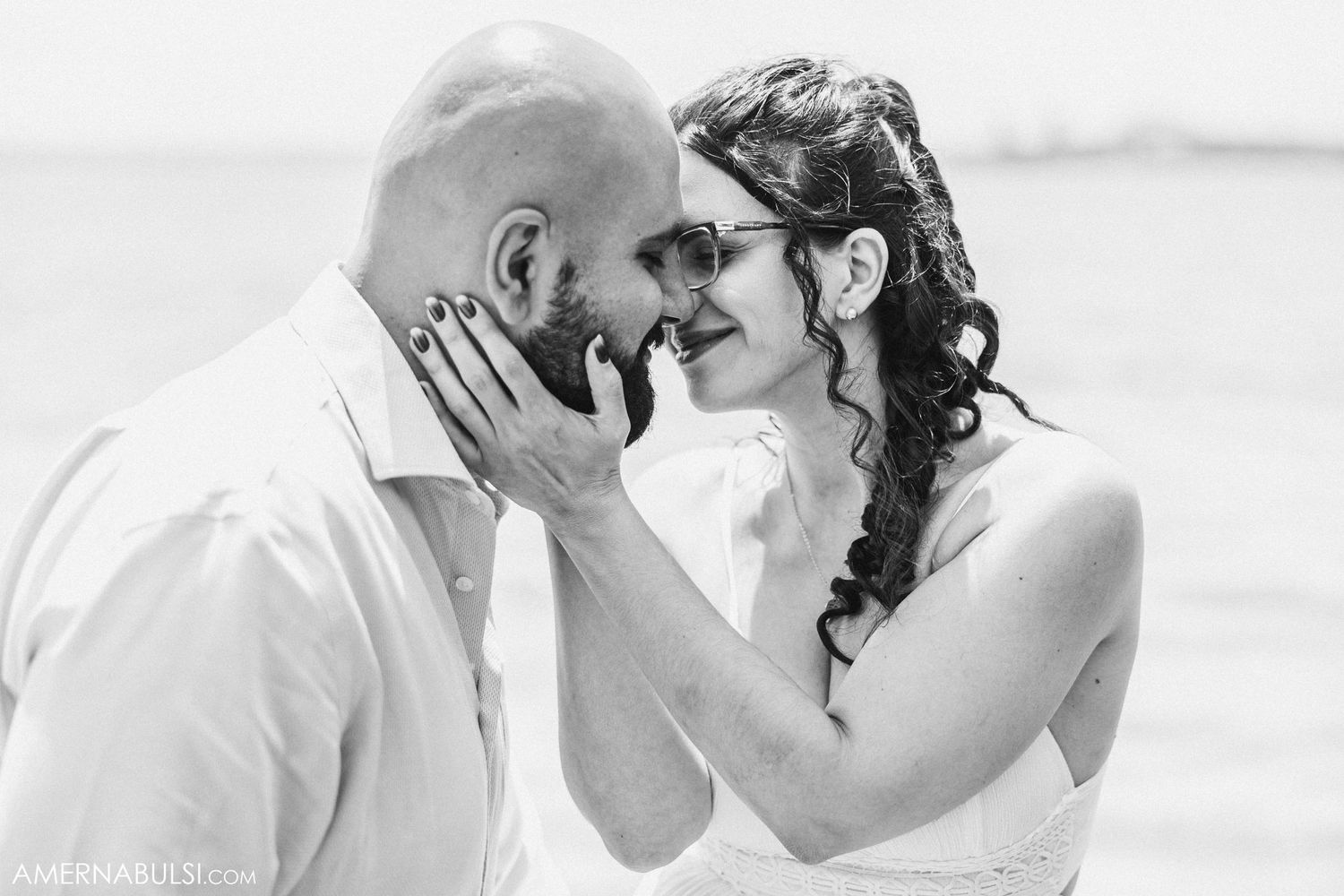 Intimate black and white portrait of a couple sharing a tender moment on the beach.
