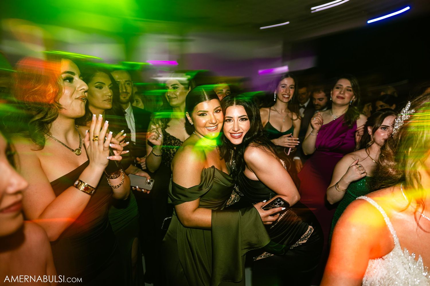 Energetic dance floor scene with green lighting effects at wedding reception.