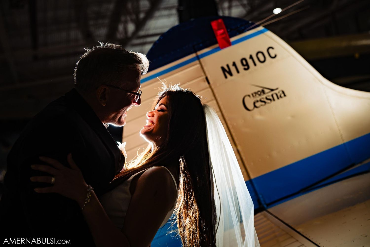 Romantic silhouette of a couple embracing in front of an illuminated airplane at night.