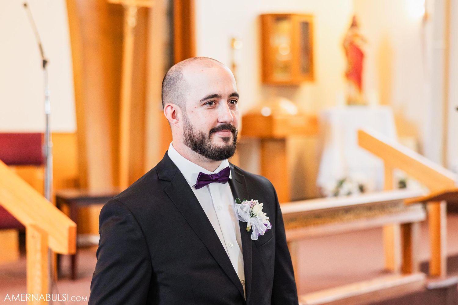 A joyful groom in formal attire stands at the altar of a church during his wedding ceremony.