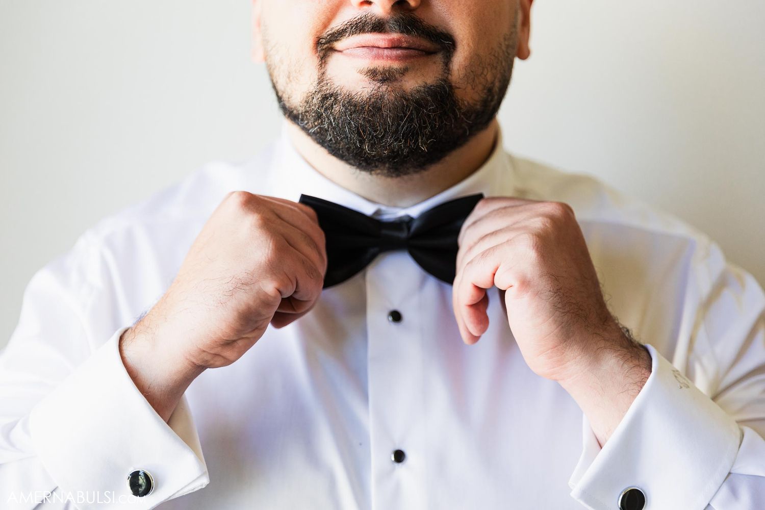 Close-up of formal white dress shirt and black bow tie being adjusted.