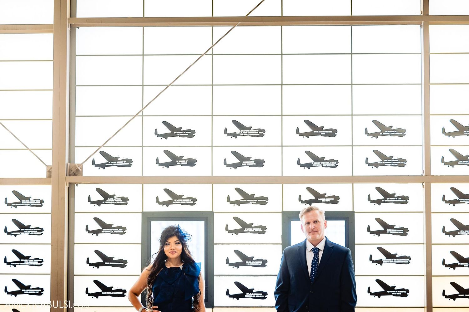 Formal portrait beneath wall of vintage aircraft silhouettes.