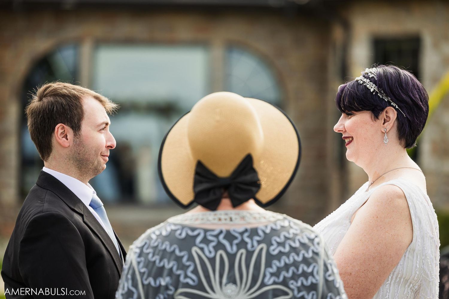 Intimate outdoor wedding ceremony with officiant in distinctive straw hat.