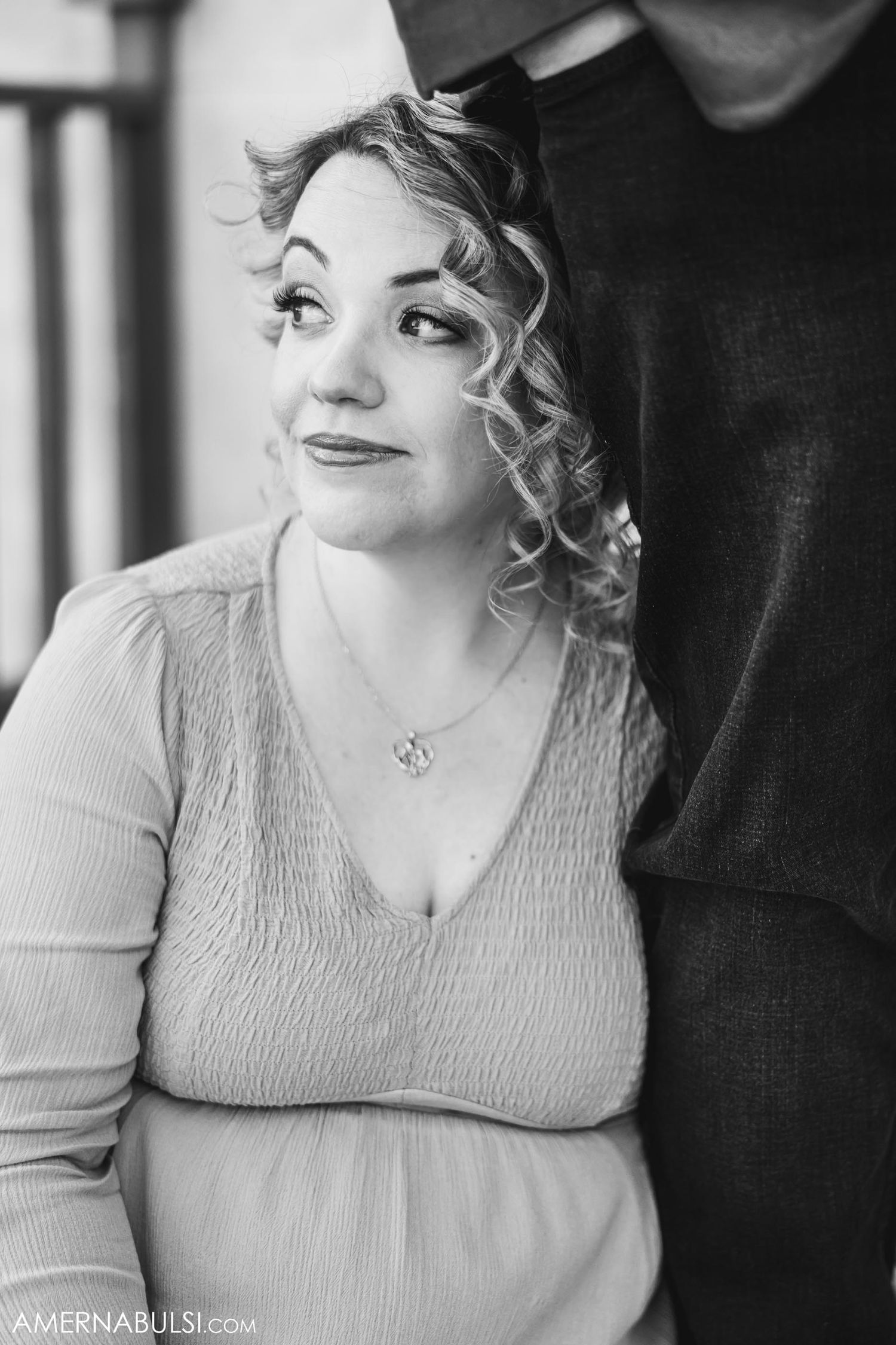 A black and white portrait of a woman with curly hair wearing a textured sweater.