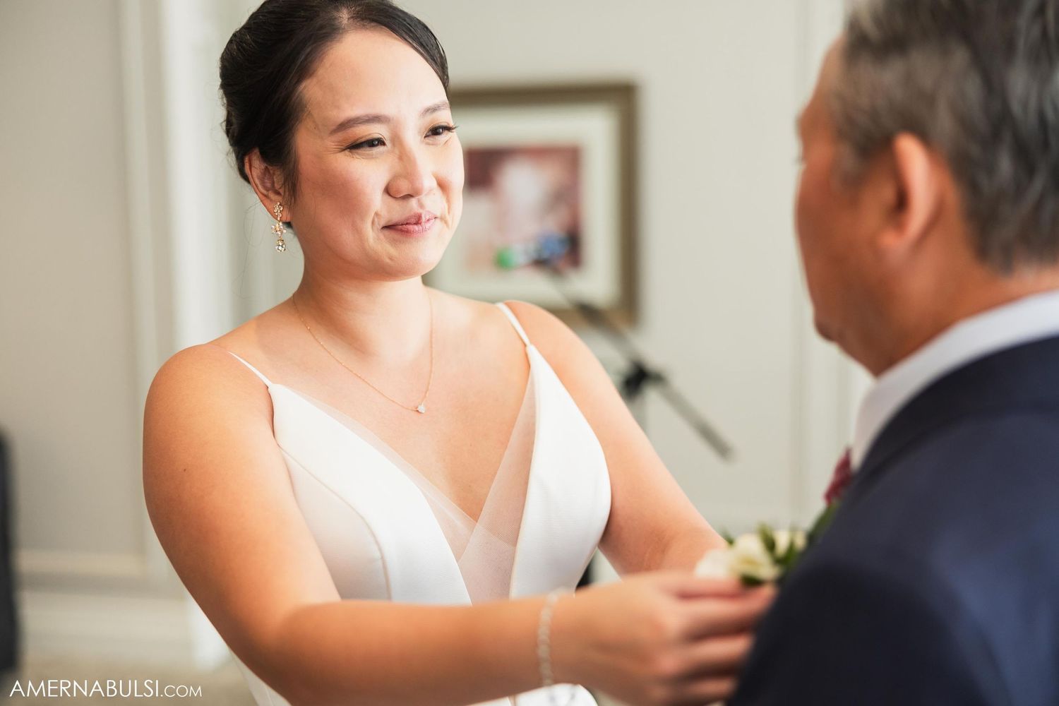 An intimate pre-wedding moment between a bride and father figure in a white room.